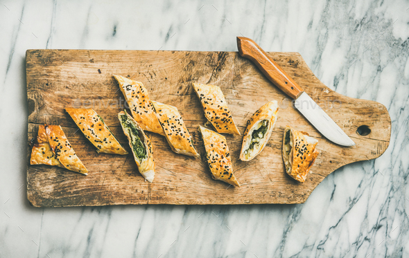 Freshly baked Turkish borek roll slices on wooden board - Stock Photo - Images