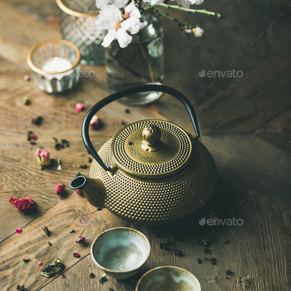 Golden iron teapot, cups, dried rose, candles, almond flowers - Stock Photo - Images