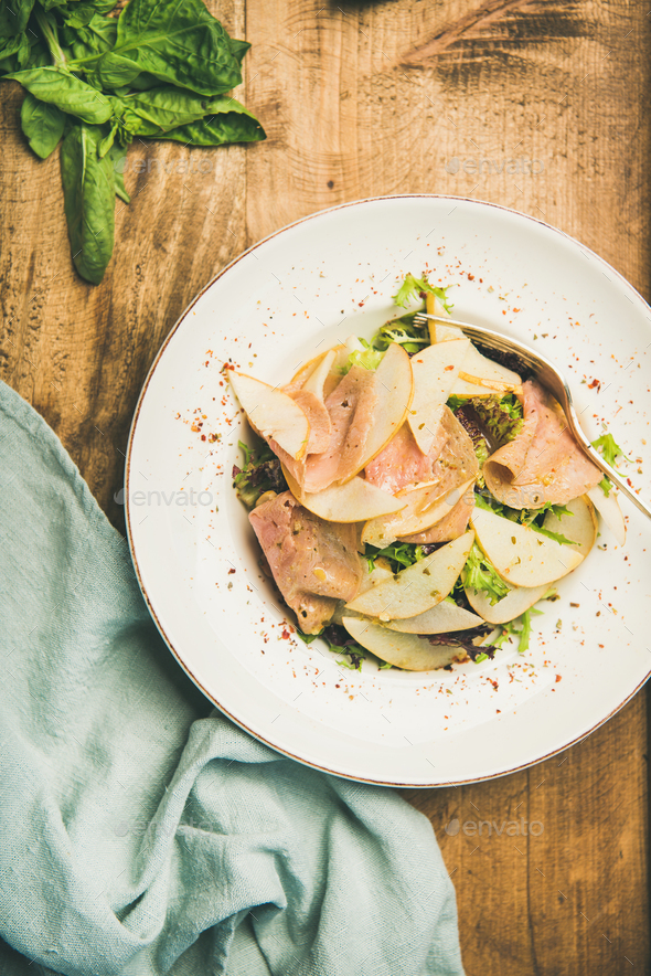 Fresh salad with smoked turkey ham and pear, wooden background - Stock Photo - Images