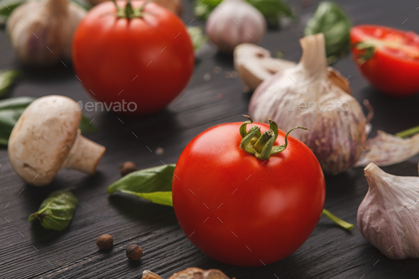 Fresh tomatoes and garlic closeup on dark rustic wood - Stock Photo - Images