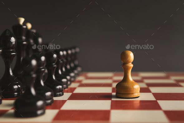 One pawn standing against set of black chess - Stock Photo - Images