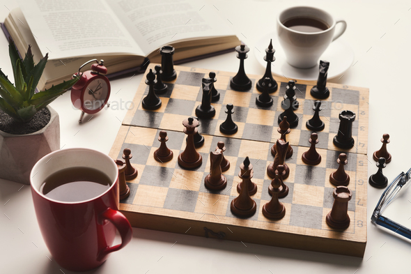 Wooden desk with chess play, book and coffee cup Stock Photo by Prostock-studio