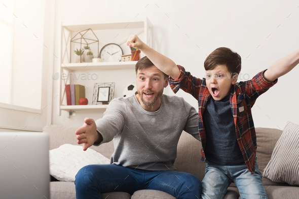 Father and son watching football on TV at home - Stock Photo - Images