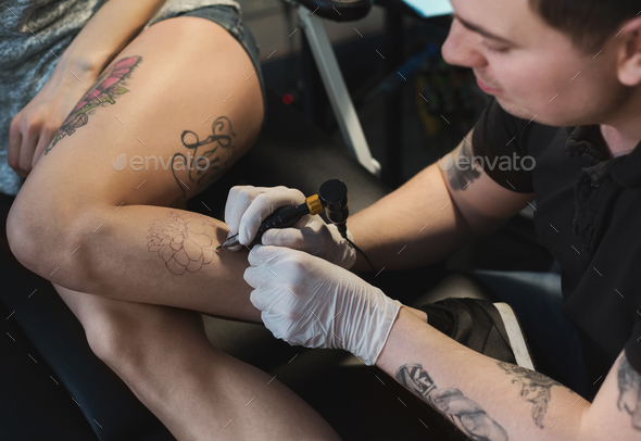 Professional tattoo artist making tattoo on leg Stock Photo by Prostock-studio