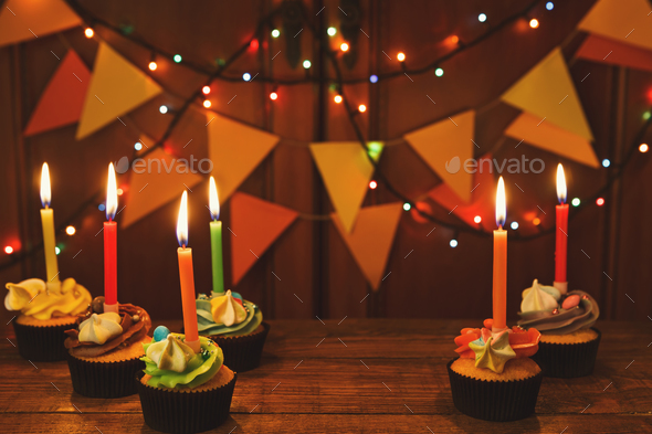 Chocolate cupcakes with candles against festive background - Stock Photo - Images