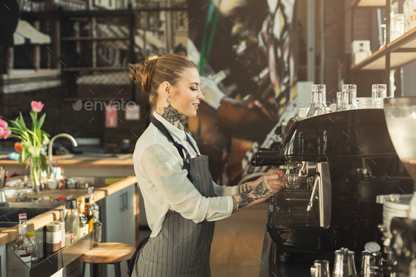 Tattooed barista making coffee in professional coffee machine - Stock Photo - Images
