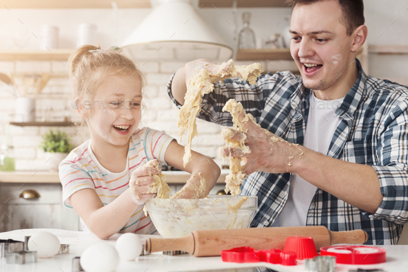 Cute little girl and father kneading dough and smiling - Stock Photo - Images