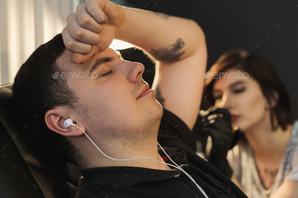 Man listening to music while doing tattoo - Stock Photo - Images