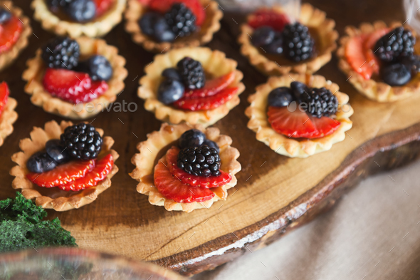 Small tartalettes with berries on wooden cutting board - Stock Photo - Images