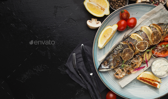 Fried fish with vegetables served at restaurant on black table - Stock Photo - Images