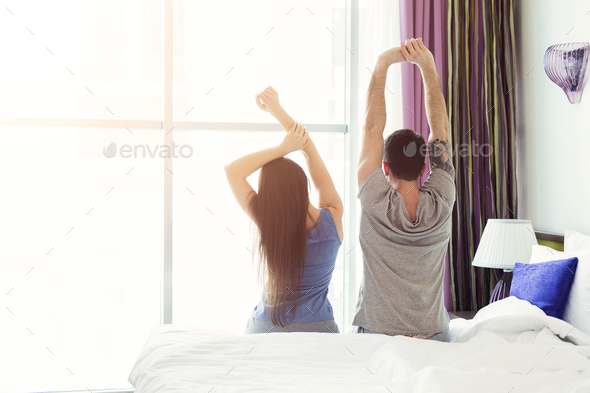 Young couple sitting on bed in hotel room - Stock Photo - Images