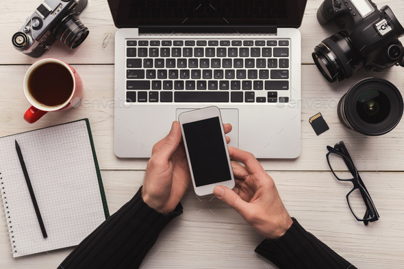 Photographer using smartphone on workplace - Stock Photo - Images