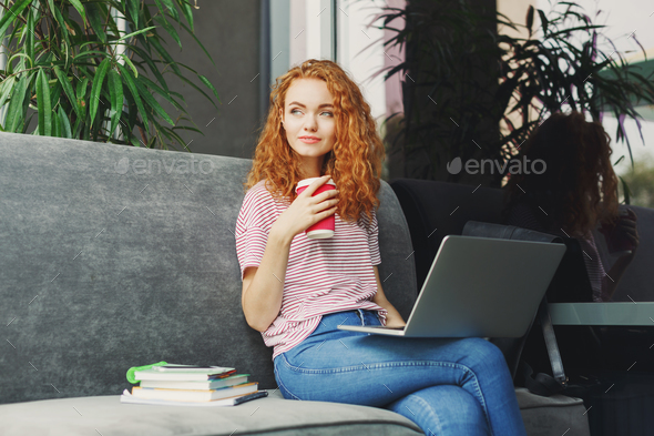 Happy young woman using laptop in cafe - Stock Photo - Images