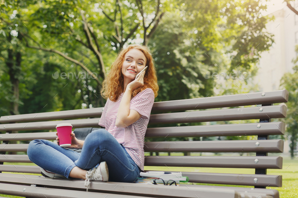Beautiful student sitting and talking on the phone outdoors - Stock Photo - Images