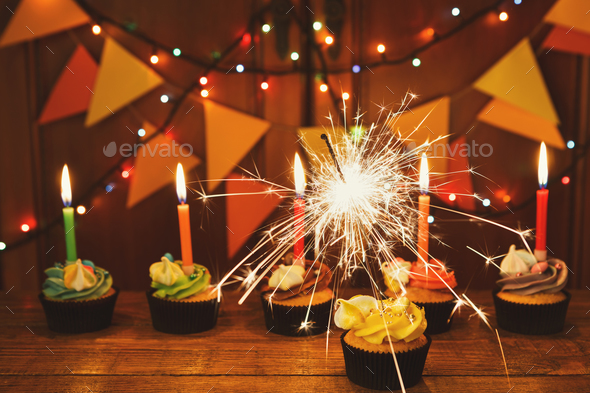 Chocolate cupcakes with candles against festive background - Stock Photo - Images