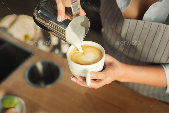 Closeup of barmen pouring milk to cappuccino cup - Stock Photo - Images