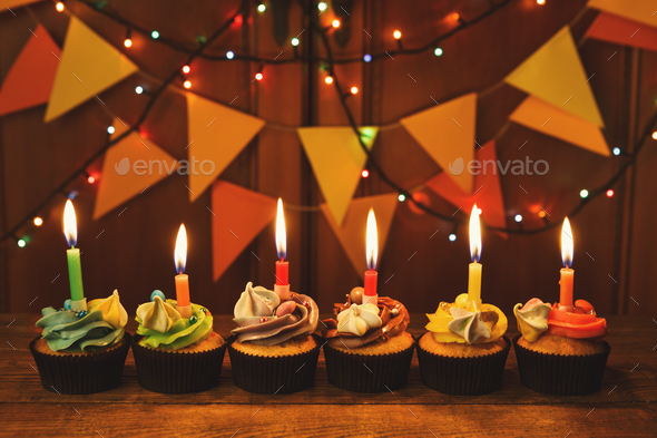 Chocolate cupcakes with candles against festive background - Stock Photo - Images