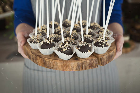 Cakepops on wooden platter in waitress hands - Stock Photo - Images