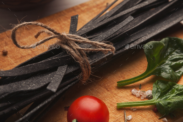 Pile of black colored fettuccine pasta on wood, closeup - Stock Photo - Images
