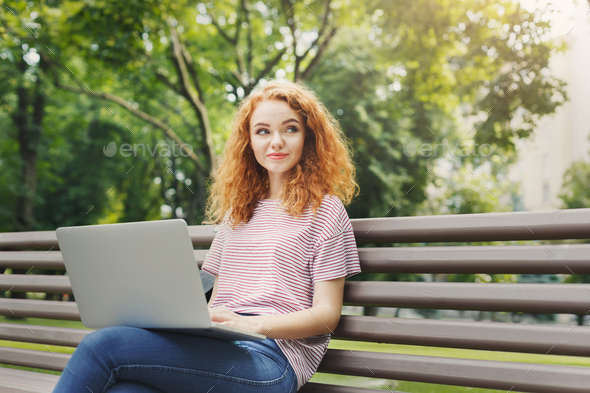 Happy woman is using laptop in the park - Stock Photo - Images