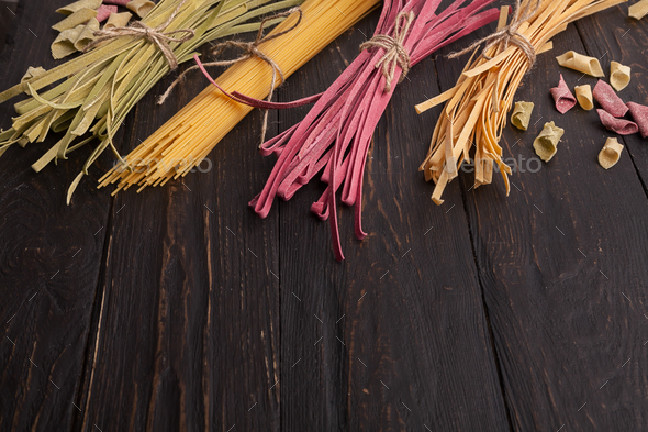 Pile of purple and green fettuccine pasta on wooden background - Stock Photo - Images