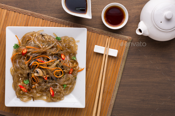 Funchoza salad on square plate on wooden table - Stock Photo - Images