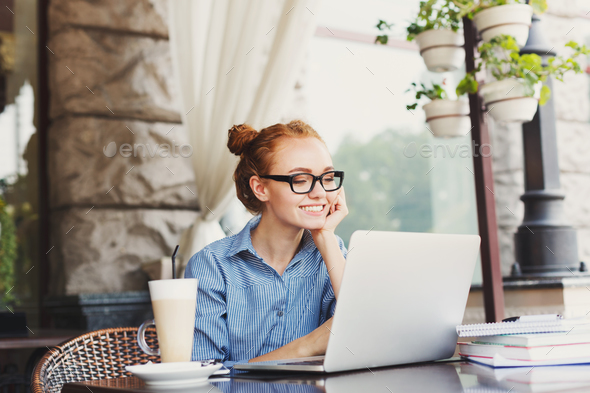 Young redhead female freelancer outdoors working with laptop - Stock Photo - Images