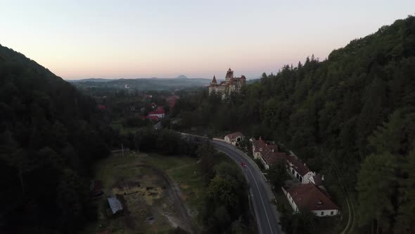 Aerial of Bran Castle and a road between hills alt