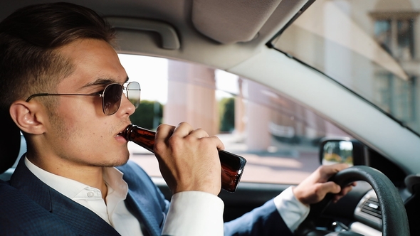 Young Businessman Drinking Beer in Car. A Man in a Bad Mood Due To a Bad Deal or a Bad News alt