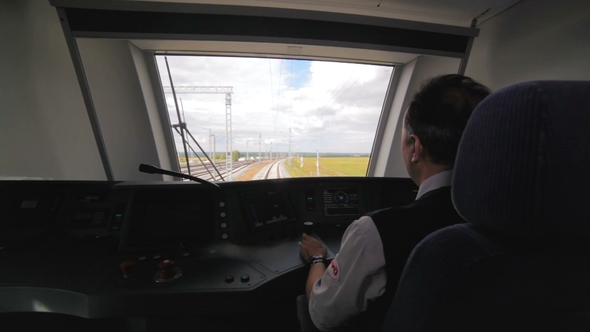 Machinist Drives Train in Cabin Among Yellow Fields alt