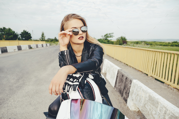 Beautiful woman posing with sunglasses on a motorbike - Stock Photo - Images