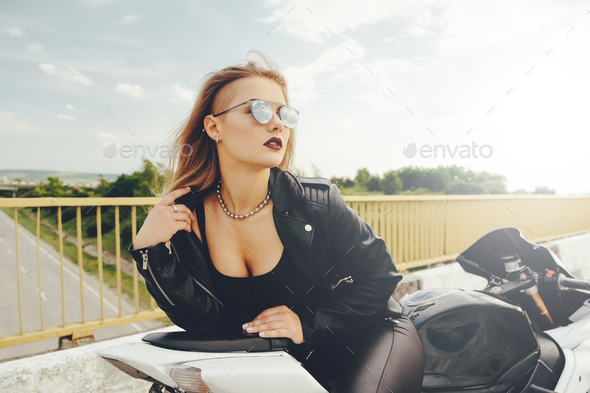 Beautiful woman posing with sunglasses on a motorbike - Stock Photo - Images