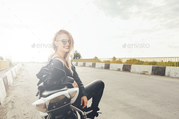 Beautiful woman posing with sunglasses on a motorbike - Stock Photo - Images