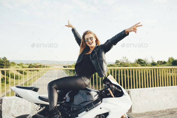 Enjoying moment woman biker posing with hands up sitting on a mo - Stock Photo - Images