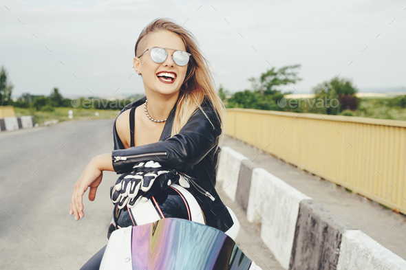 Beautiful woman posing with sunglasses on a motorbike - Stock Photo - Images