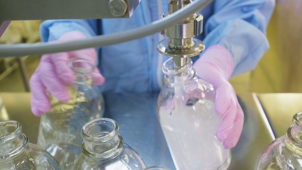 Worker Pours Liquid Into Capacites in Chemical Laboratory alt