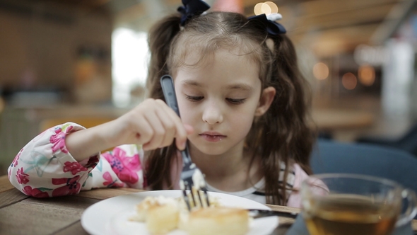 Happy Child Is Eating a Cheesecake and Drinking Tea in a Cafe, Stock ...