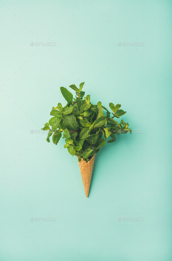 Waffle cone with fresh mint over blue background, vertical composition - Stock Photo - Images