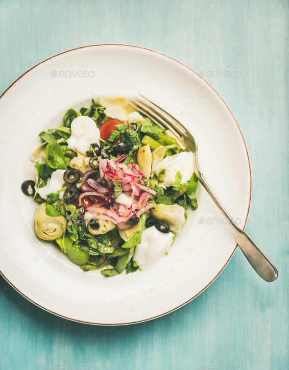 Fresh green summer salad with artichokes over blue wooden background - Stock Photo - Images