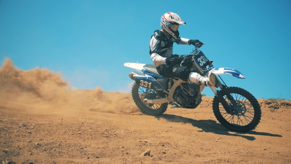 Motorcyclist Is Performing a Trick While Driving a Motorbike Through Dust alt