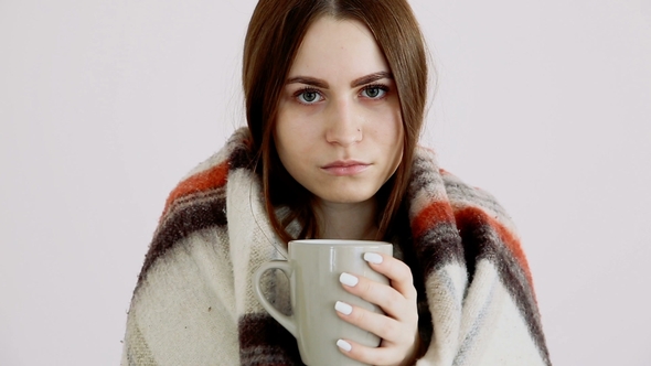 Cold Girl of European Appearance in a Woolen Blanket Is Drinking Hot Tea