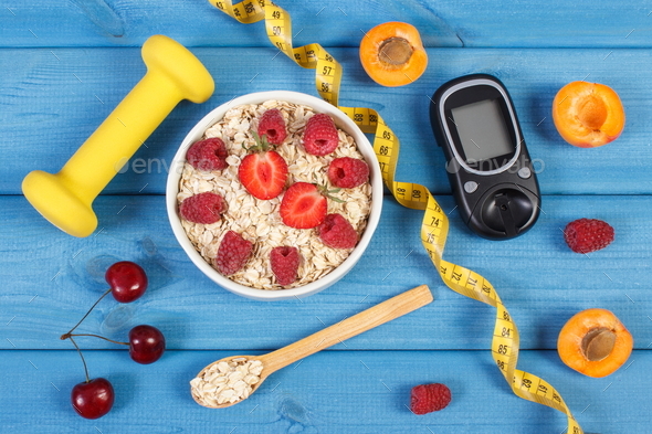Glucose meter for measuring sugar level, oatmeal with fruits and dumbbells - Stock Photo - Images