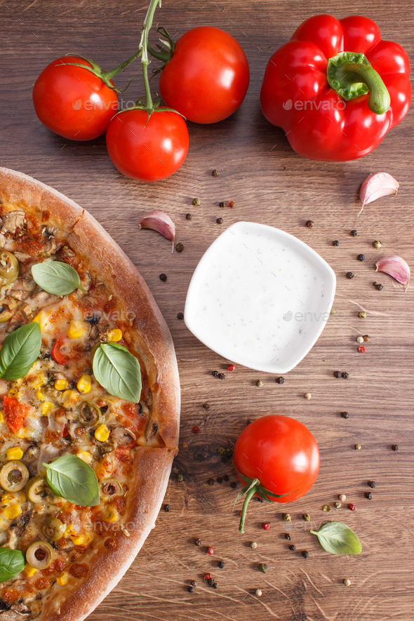 Vegetarian pizza and ingredients with spices on board, fast food concept Stock Photo by ratmaner