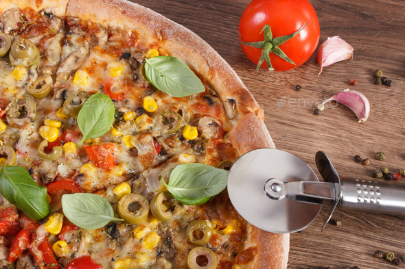 Pizza cutter with vegetarian pizza, ingredients with spices, fast food concept - Stock Photo - Images