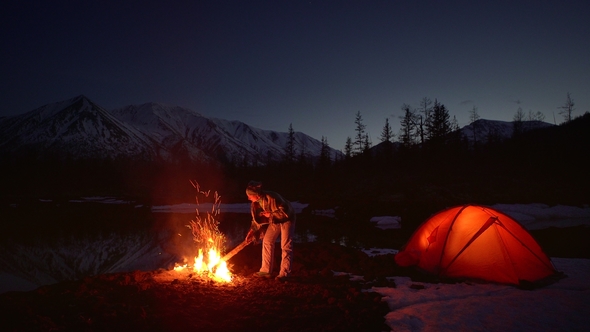 Woman Warming Up in a Camping By the Fire in Mountains alt