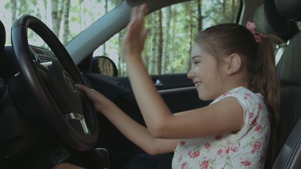 Cheerful Girl Pressing Car Horn on Steering Wheel alt