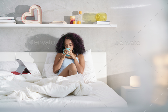 Woman Drinking Coffee Watching Movie In Bed on Sunday - Stock Photo - Images