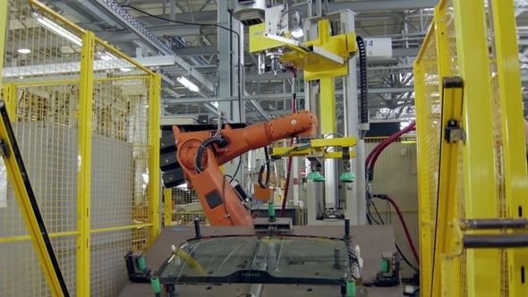Workerman Is Installing a Car Windows on a Platform of Robotic Machinery for Hermetization