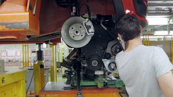 Installing an Engine in a Car on an Automobile Plant, Worker Is Using Auto Hydraulic Lift