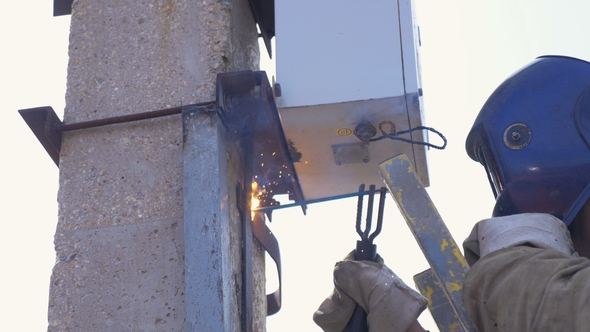 Worker Carries Out Welding on Concrete Support alt